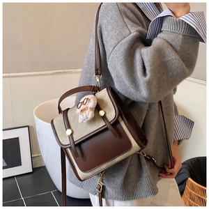 Détail d'un mini sac à dos vintage bicolore avec un pendentif lapin et des crochets en métal