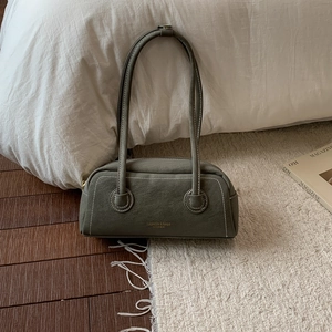 Detail of olive green suede cylinder shoulder bag with gold logo and white stitching