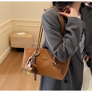 Detail view of brown faux suede tote bag with cute bear charm and fashion label