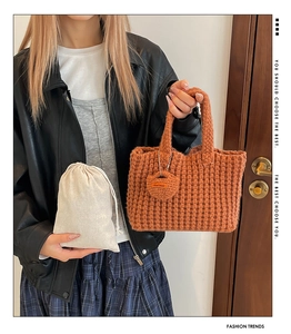 Close-up of caramel hand-woven knit tote bag with Hand Made tag and dust bag