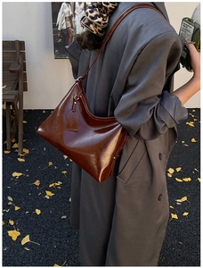 Detail of caramel brown glossy leather hobo bag with vintage texture and long strap