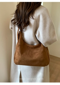 Détail macro du sac hobo en daim caramel avec large bandoulière et texture rétro minimale