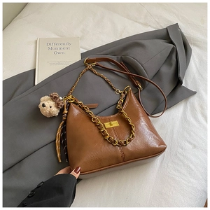 Detail of brown vintage crossbody bag with gold chain strap and cute bear charm