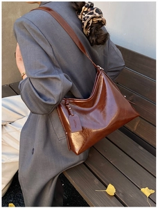 Close-up of a brown glossy leather tote bag with a vintage brand tag and smooth finish