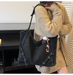 Detail of black tote bag with white contrast stitching and side buckle straps for women