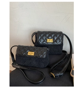 Détail du sac bandoulière noir matelassé avec fermoir rotatif doré et texture velours