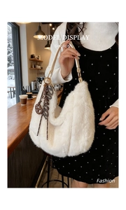 Gros plan détaillé du sac hobo en fausse fourrure blanche avec bandoulière beige et boucles dorées