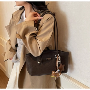 Detail view of dark brown tote bag with star charms on a model in a trench coat