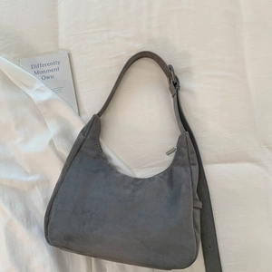 Vue de dessus d'un sac hobo en daim gris avec bandoulière réglable sur fond minimaliste