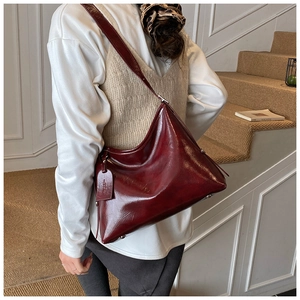 Detail of burgundy wax leather tote bag with elegant side tag and smooth glossy texture
