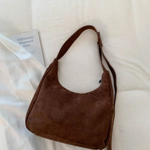 Gros plan du sac hobo en daim marron avec bandoulière réglable et fermeture éclair argentée