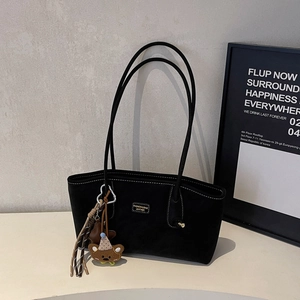 Close-up of black suede tote bag with contrast stitching and decorative animal charm