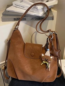 Braune Vintage PU-Leder Tragetasche mit Bärenanhänger auf Retro-Büchern Hintergrund