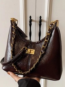 Chocolate brown hobo bag with gold chain and polished leather shown held by a model