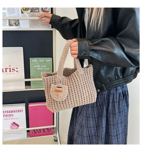Detail of hand-woven beige tote bag with a knitted heart charm and 'Hand Made' label