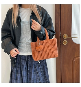 Detailed knit texture of an orange handmade crochet tote bag with a small matching charm