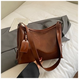 Detail of dark brown glossy leather tote bag showing smooth texture and branded tag