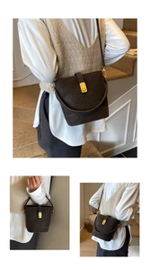 Detailansicht der dunkelbraunen Beuteltasche mit goldenem Drehverschluss und zwei Gurten