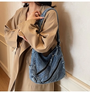Détail d'un grand sac cabas en jean vintage avec fermetures éclair porté par un modèle