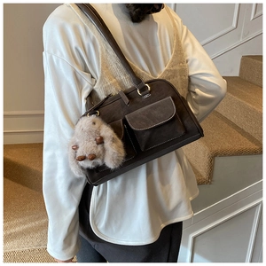 Detail of dark brown suede Boston bag featuring white contrast stitching and plush bunny charm