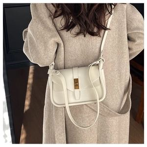 Dettaglio della borsa a tracolla bianco crema con chiusura dorata su cappotto elegante