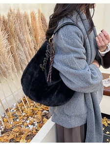 Détail du sac hobo en fausse fourrure noire avec breloques et bandoulière sur le mannequin