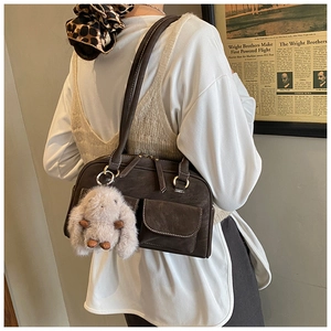 Detail view of retro brown shoulder bag with pocket flaps and silver ring hardware