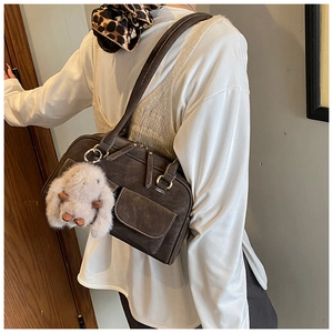 Close-up of retro brown Boston bag with contrast stitching and plush bunny charm