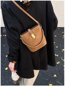 Nahaufnahme braune Wildleder-Beuteltasche mit Metallschnalle im herbstlichen Streetstyle
