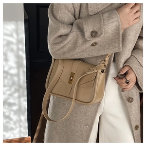 Dettaglio borsa a tracolla kaki con chiusura a scatto dorata su outfit elegante