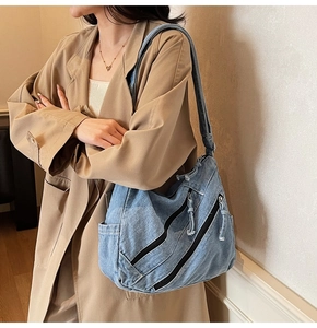 Détail du sac à bandoulière en denim bleu clair avec deux poches zippées inclinées