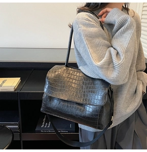 Close-up detail of black crocodile pattern faux leather shoulder bag with glossy finish