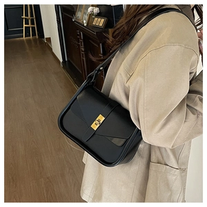 Dettaglio di una borsa a tracolla in pelle nera con fibbia rettangolare in metallo oro