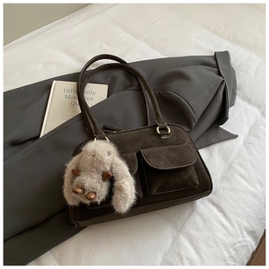 Detail of vintage brown suede shoulder bag with dual pockets and a plush bunny charm