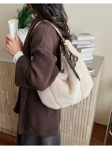 Détail de la texture d'un sac à bandoulière en fausse fourrure crème avec breloques brunes