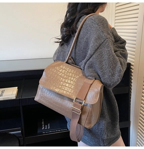 Brown crocodile pattern tote bag featuring dual straps shown in a modern interior setting