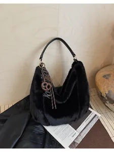 Détail du sac hobo en fourrure noire avec poignée en cuir et breloque pâtisserie brune