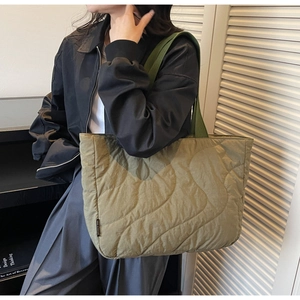 Close-up of olive green quilted tote bag showing wave stitching and side brand label