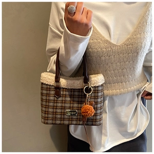 Detail der karierten Woll-Beuteltasche mit Lammfellbesatz und orangefarbenem Anhänger