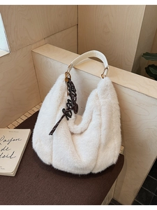Détail du sac hobo en fausse fourrure blanche avec boucles dorées et pendentif