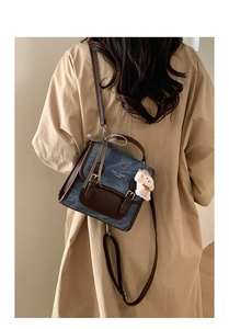 Detail of vintage denim backpack with brown leather trim and cute teddy bear charm accessory