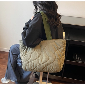 Detailed close-up of olive green tote bag featuring wave quilted fabric and side label