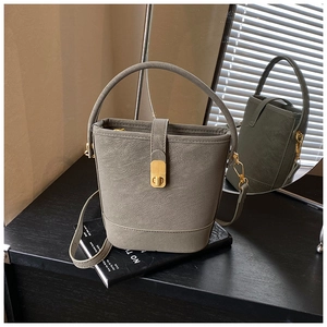 Detailansicht graue Beuteltasche mit Litschi-Textur und goldenem Metallschloss auf Tisch