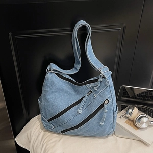 Détail du sac cabas en denim bleu clair avec trois poches zippées et bandoulière large