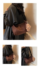 Detail of a brown suede hobo bag featuring a black wide strap and a cute bear charm