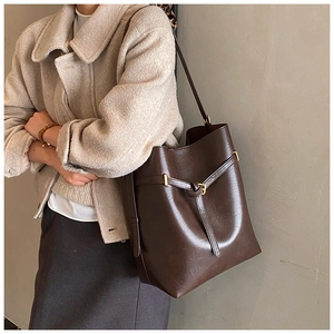 Detailed view of the dark brown leather bucket bag showing soft texture and strap