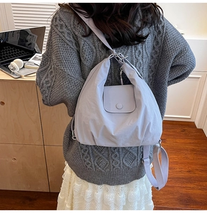 Detailed view of grey-purple nylon backpack on a model in a cozy indoor home setting