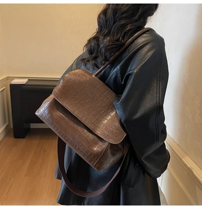 Detail of vintage brown crossbody bag with crocodile pattern and wide textile strap