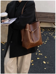 Brown leather large tote bag with buckle detail shown in an outdoor lifestyle setting