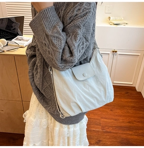 Close-up of lightweight grey nylon crossbody bag with textured fabric and flap closure
